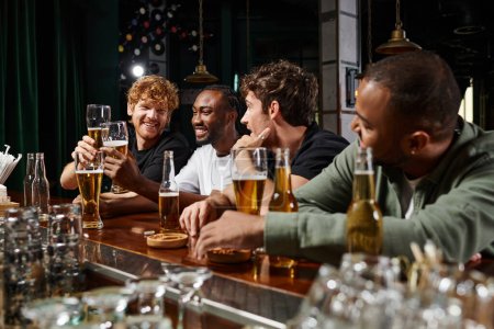 hombres multiculturales pasar tiempo juntos, charlando y brindando con cerveza, amigos varones en el bar
