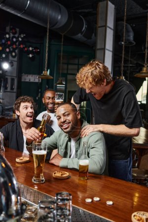 redhead man touching shoulders of african american groom during bachelor party, male friendship
