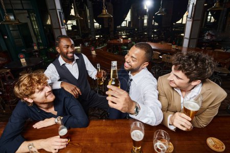 Glückliche Kollegen in festlicher Kleidung plaudern und trinken Bier in der Bar, verbringen Zeit miteinander nach der Arbeit