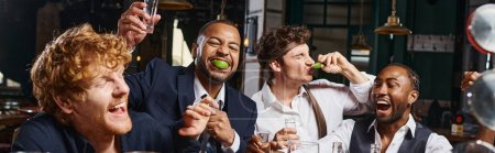 banner of four happy and drunk multiethnic friends in formal wear drinking tequila in bar after work