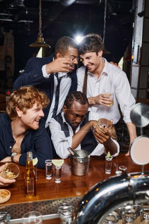 Photo for Drunk and funny interracial friends hugging after drinking several alcohol drinks in bar after work - Royalty Free Image