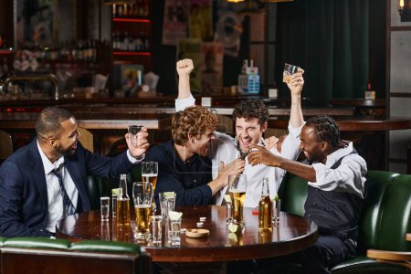 Betrunkener hebt Hände mit Glas Whisky in der Nähe von multiethnischen Freunden in Bar, Feierabend-Spaß