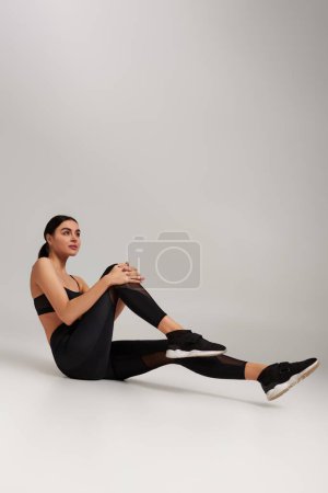 Foto de Deportista en uso activo con rastreador de fitness en la muñeca ejercicio sobre fondo gris, determinación - Imagen libre de derechos