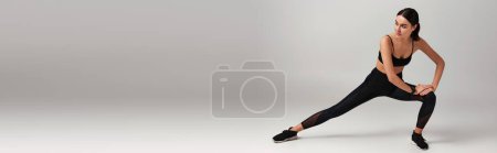 Foto de Deportista en uso activo con rastreador de fitness en la muñeca haciendo embestidas sobre fondo gris, pancarta - Imagen libre de derechos