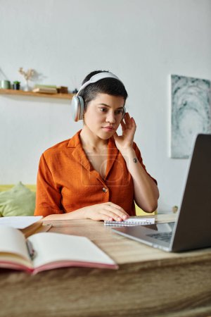 vertical shot of concentrated female student with headphones studying at her laptop, education