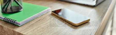 Photo for Object photo of mobile phone on table next to laptop and pens in stand on notebook, education - Royalty Free Image