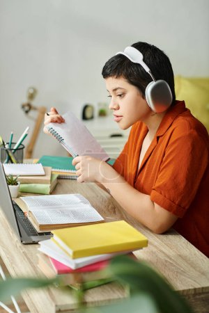 vertical shot of young attractive student with headphones studying hard and looking at laptop