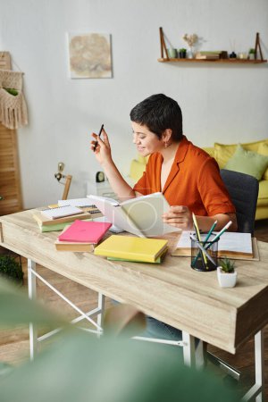 vertical shot of cheerful young woman in orange shirt smiling happily while studying hard, education