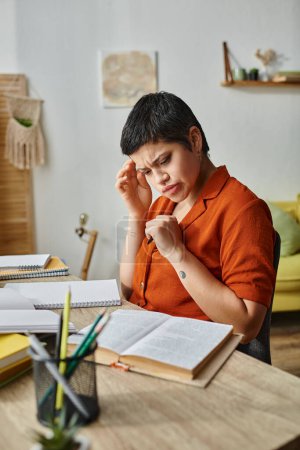 confused concentrated woman sitting at table and studying hard on her materials, education at home