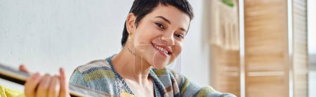 Photo for Smiling young woman attending remote guitar lesson and smiling at camera, education at home, banner - Royalty Free Image