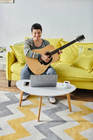 Photo for Vertical shot of young woman learning how to play guitar on remote music lesson, education at home - Royalty Free Image