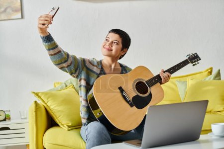 alegre joven mujer tomando selfie con la guitarra durante la lección de música en línea, la educación en casa