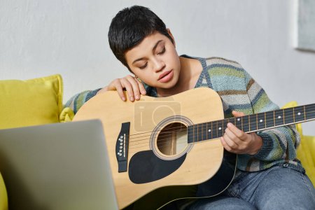 Foto de Mujer joven concentrada aprendiendo a tocar la guitarra en una lección de música remota, educación en casa - Imagen libre de derechos