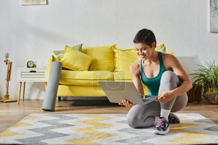 joyous young woman standing on one knee on floor smiling at laptop camera, fitness and sport