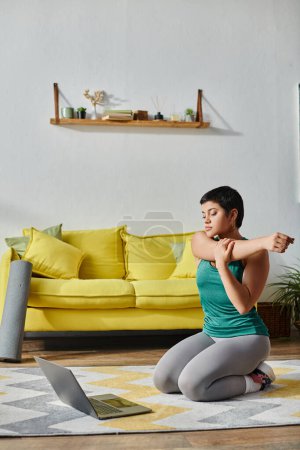 vertikale Aufnahme einer jungen Frau in Sportkleidung beim Stretching während eines Online-Fitnessunterrichts, Fitness
