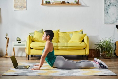 good looking woman in sportswear stretching on floor during online sport lesson, fitness and sport