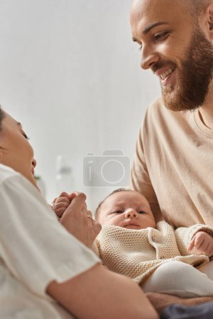 Photo for Vertical shot of young happy parents in homewear holding their newborn baby boy, family concept - Royalty Free Image