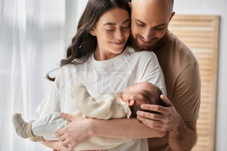 hermosos padres felices abrazando y sosteniendo a su bebé recién nacido amorosamente, concepto de familia