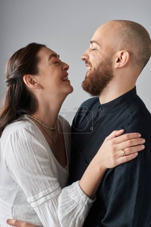 Photo for Vertical shot of happy laughing couple hugging each other lovingly and smiling at each other - Royalty Free Image