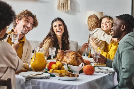 Téléchargez les photos : Heureux multiculturel famille et amis ayant dîner de vacances ensemble le jour de Thanksgiving - en image libre de droit