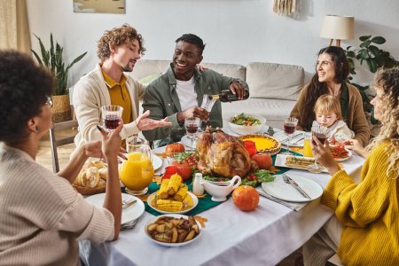 multicultural family enjoying Thanksgiving meal at festive table, mother and child near turkey mug #678866122