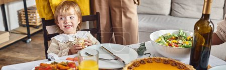Téléchargez les photos : Bannière de jeune fille regardant loin et souriant près de tarte à la citrouille pendant la célébration de Thanksgiving - en image libre de droit