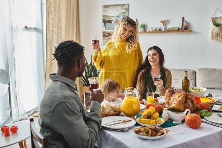 joyful lgbt family celebrating Thanksgiving with toddler baby girl and african american man