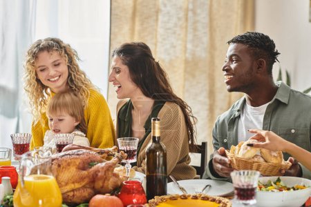 gebratener Truthahn in der Mitte des Tisches, glückliche interrassische Familie feiert gemeinsam Thanksgiving