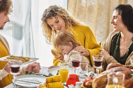 joyeuse famille multiraciale profitant d'un délicieux dîner tout en se rassemblant sur Thanksgiving, dinde rôtie