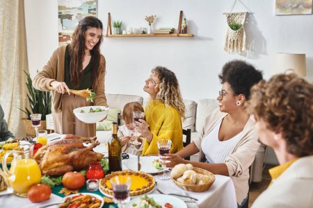 happy woman serving salad to interracial friends and family during Thanksgiving celebration at home