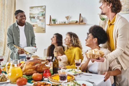 Thanksgiving traditions, happy multiethnic friends and family gathering at table with turkey