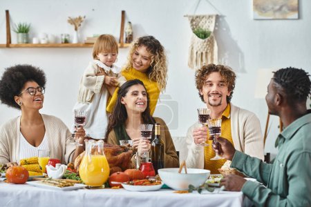Joyeux Thanksgiving, amis multiculturels joyeux et famille acclamant avec des verres de vin rouge