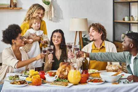 Happy Thanksgiving, cheerful multiethnic friends and family clinking glasses of wine near turkey