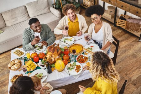 Feliz Acción de Gracias, alegres amigos interracial y reunión familiar en la mesa festiva con pavo