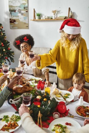 Fröhliche multiethnische Freunde und Familie mit Weihnachtsmannhüten jubeln bei der Weihnachtsfeier