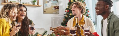 heureuse famille multiraciale riant et savourant le déjeuner avec dinde et vin, Noël, bannière