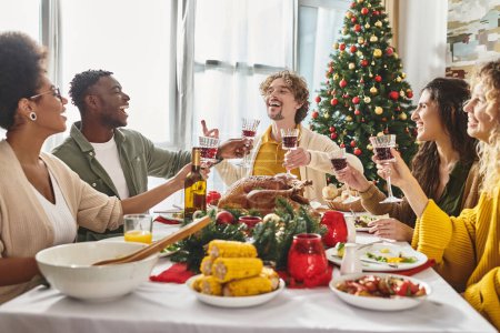 big multiracial family laughing and gesturing while enjoying wine and festive lunch, Christmas