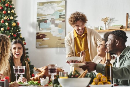Foto de Gran familia alegre multicultural sentada en la mesa de Navidad riendo y disfrutando de la fiesta de vacaciones - Imagen libre de derechos