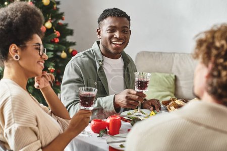 young african american couple sitting at festive table enjoying holiday lunch with family, Christmas