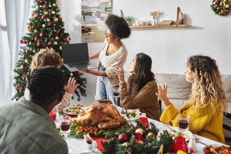 familia multicultural reunida en la fiesta de vacaciones saludando y haciendo gestos en la cámara del ordenador portátil, Navidad