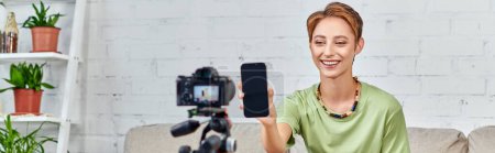 Photo for Vegetarian woman holding smartphone with blank screen near digital camera during video blog, banner - Royalty Free Image
