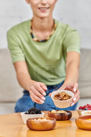 cropped view of woman with walnuts near blackberries, chickpeas and various plant-based products