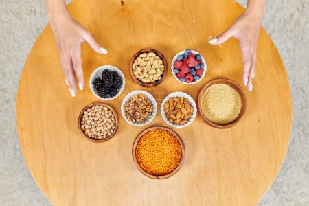 top view of female hands over table with assortment of plant-based vegetarian food on table at home