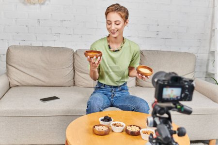 Téléchargez les photos : Femme heureuse avec bols de couscous et lentilles près de l'appareil photo numérique et divers aliments à base de plantes - en image libre de droit