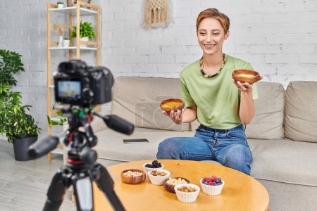 Téléchargez les photos : Femme heureuse avec couscous et lentilles près de l'ensemble de nourriture végétarienne et appareil photo numérique flou - en image libre de droit