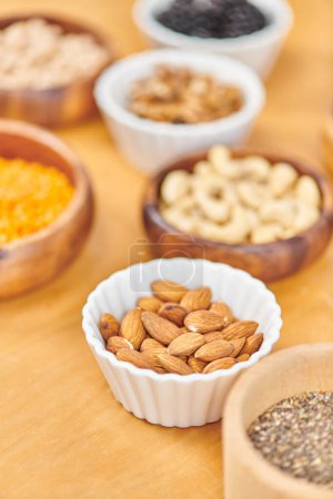 bowl with delicious almonds near plant-based food on blurred background, vegetarian nutrition