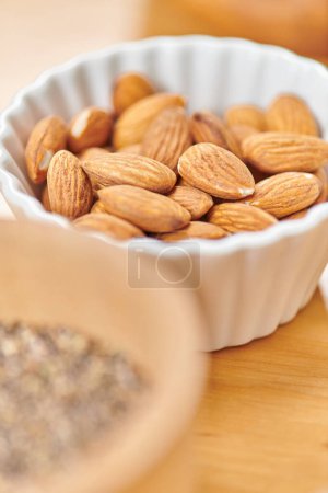close up view of delicious almonds in white ceramic bowl on blurred foreground, plant-based diets