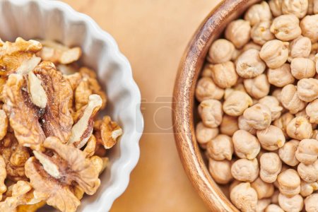 top close up view of chickpeas and walnuts in wooden and ceramic bowls, plant-based diets concept