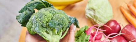 top view of vegetarian woman with broccoli over fresh fruits and vegetables, horizontal banner