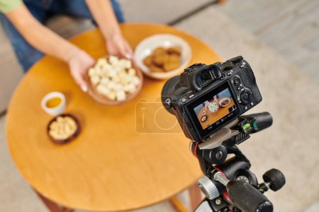 Fokus auf Digitalkamera in der Nähe von Frauen mit Teller mit vegetarischem Tofu-Käse in der Nähe vegetarischer Mahlzeit